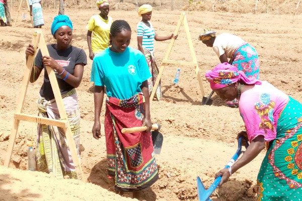 A group of Kenyan women using A frames to determine land levels in a permaculture garden